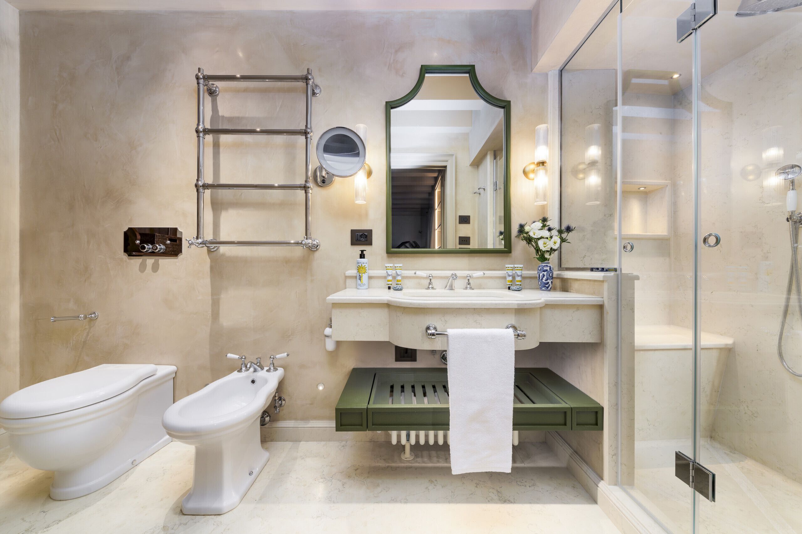 Une salle de bain comprenant des toilettes, un bidet, un lavabo avec un miroir et une douche.