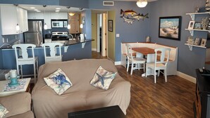 Un salon chaleureux avec un canapé, une table à manger et une cuisine en arrière-plan.