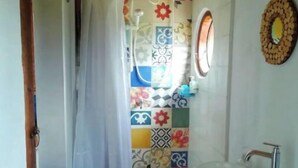 Une salle de bain avec une douche, un lavabo, un miroir et un mur carrelé.