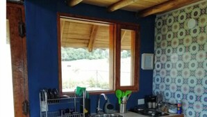 Une cuisine de taille réduite, dotée d’un plan de travail en bois, d’un évier et d’une fenêtre située au-dessus.