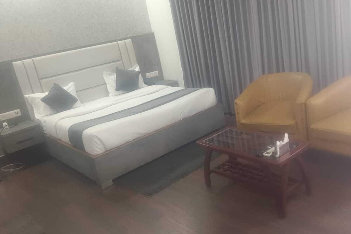 Une chambre d’hôtel comprenant un lit, deux fauteuils, une petite table et une table de chevet.