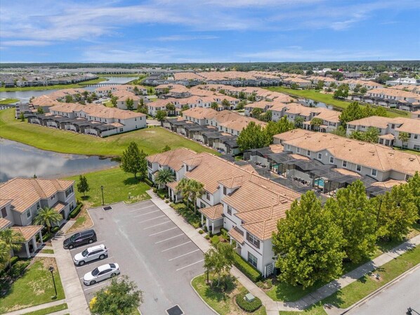 A residential area with multiple houses, a parking lot, and a body of water.