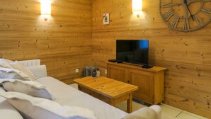 Puupaneloitu huone, jossa on sänky, pöytä, televisio ja seinäkello.