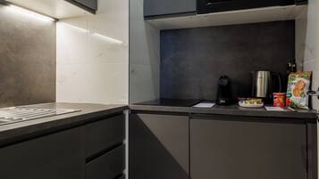 Una cucina moderna con mobili scuri, un forno a microonde, un bollitore e una macchina per il caffè.