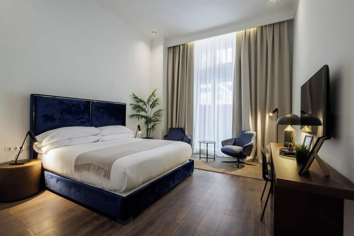 Un dormitorio moderno con una cama grande, un escritorio, una silla y un televisor.