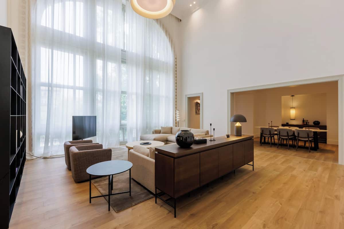 Una sala de estar moderna con un sofá, una mesa de centro y un televisor. Hay un comedor con sillas y una mesa.
