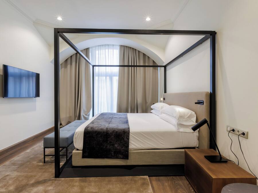 A four-poster bed with a flat-screen TV, a bedside table, and a power outlet.