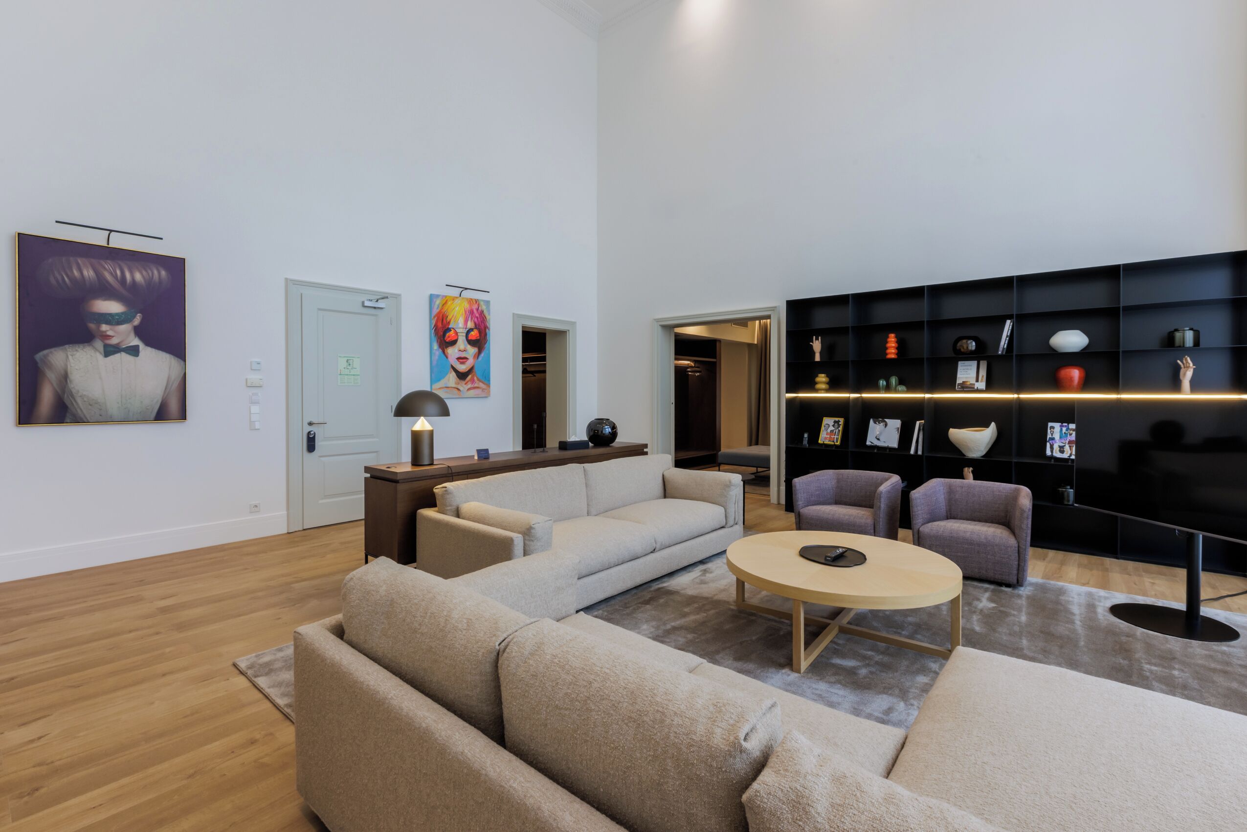 Un saló modern amb un sofà modular, una taula de centre rodona i un prestatge negre amb objectes decoratius.