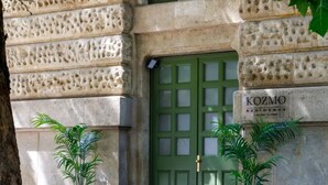 A stone building with a green door and a sign reading 'KOZMO RESIDENCE.' There are two potted plants in front of the door. - Apartments Kozmo Residences Budapest (Budapest)