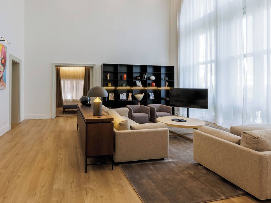 Un salon moderne avec un plancher en bois, un ensemble de canapés, un téléviseur et une étagère noire.