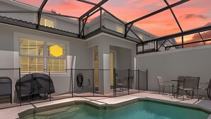 Ein modernes Haus mit Swimmingpool, überdachter Terrasse und Blick auf den Sonnenuntergang.