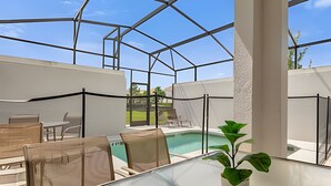 Ein überdachter Außenbereich mit Pool, Sitzgelegenheiten und einer Pflanze im Topf.