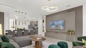 A modern living room with a grey sofa, green ottomans, a coffee table, and a TV mounted on the wall. - Modern Paradise on Windsor Cay: Luxurious 8BD Home (Clermont)