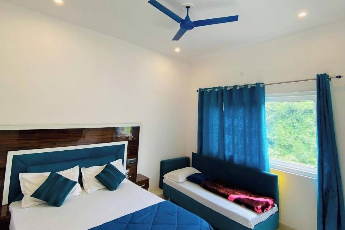 Un dormitorio con una cama grande, una cama más pequeña, un ventilador de techo y una ventana con cortinas.