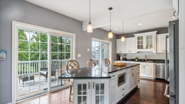 A modern kitchen with white cabinetry, a large island, and pendant lighting. - South Side home with garage, game room, gym & deck near downtown, stadiums and Carson Street (Pittsburgh)