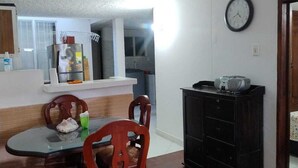 A dining area with a table and chairs, a refrigerator, a clock, and a cabinet. - Apartment Iwoo HR with WiFi, AC in welcoming Villavicencio (Villavicencio)