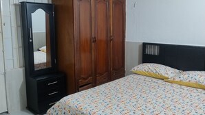 A bedroom with a wooden wardrobe, a mirror, a bed with floral bedding, and a white tiled floor. - Apartment Iwoo HR with WiFi, AC in welcoming Villavicencio (Villavicencio)