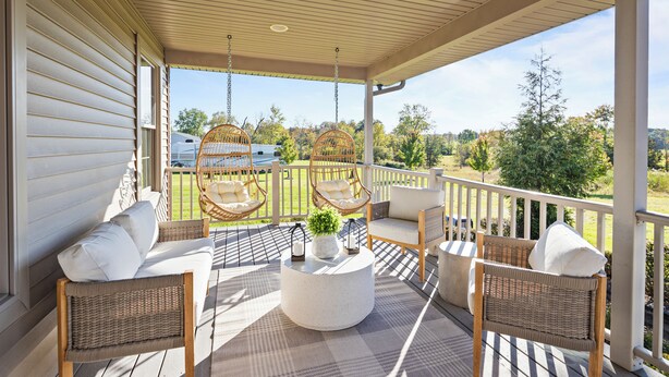 A covered porch with wicker furniture, a round coffee table, and a view of a green landscape. - Elegant Home w/7BRs, Game Room, Luxury Yard, Pool (Chester)