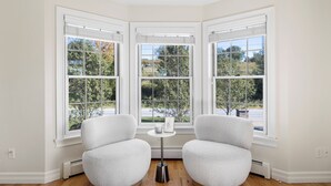 A corner room with three large windows, a small table, and two white chairs. - Elegant Home w/7BRs, Game Room, Luxury Yard, Pool (Chester)