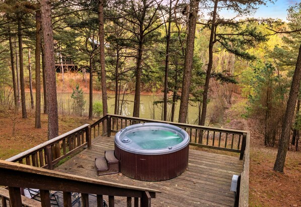 Un jacuzzi en una terraza de madera rodeado de árboles.