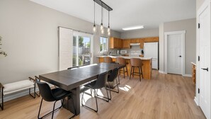 Una cocina moderna con armarios de madera, una isla central y un comedor con una mesa larga y sillas.