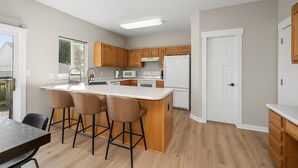 Una cocina moderna con armarios de madera, un refrigerador blanco y una isla grande con taburetes de bar.
