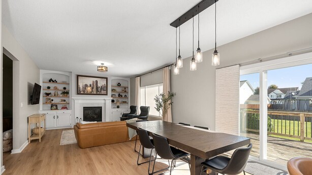 Una cocina moderna con comedor, piso de madera y un amplio ventanal con vista al jardín.