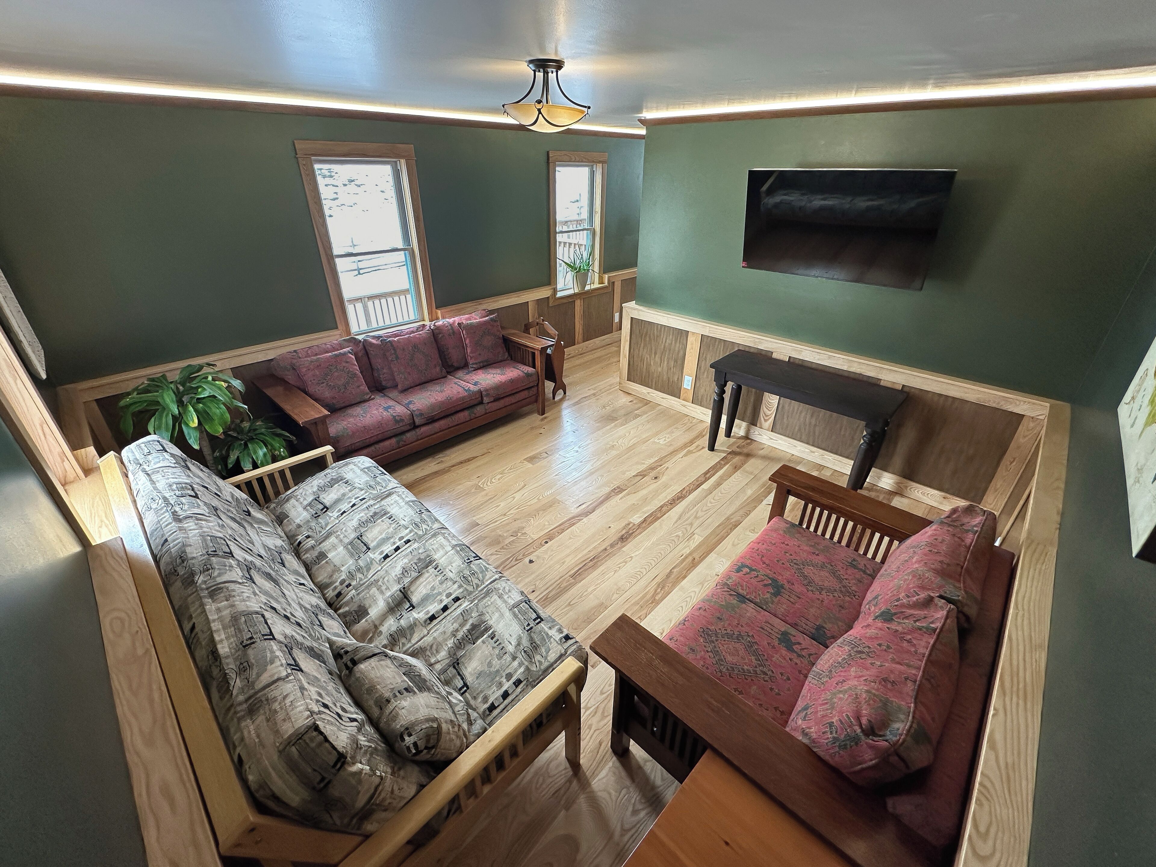 Un salon chaleureux avec un banc en bois, un canapé rouge et un divan à motifs.