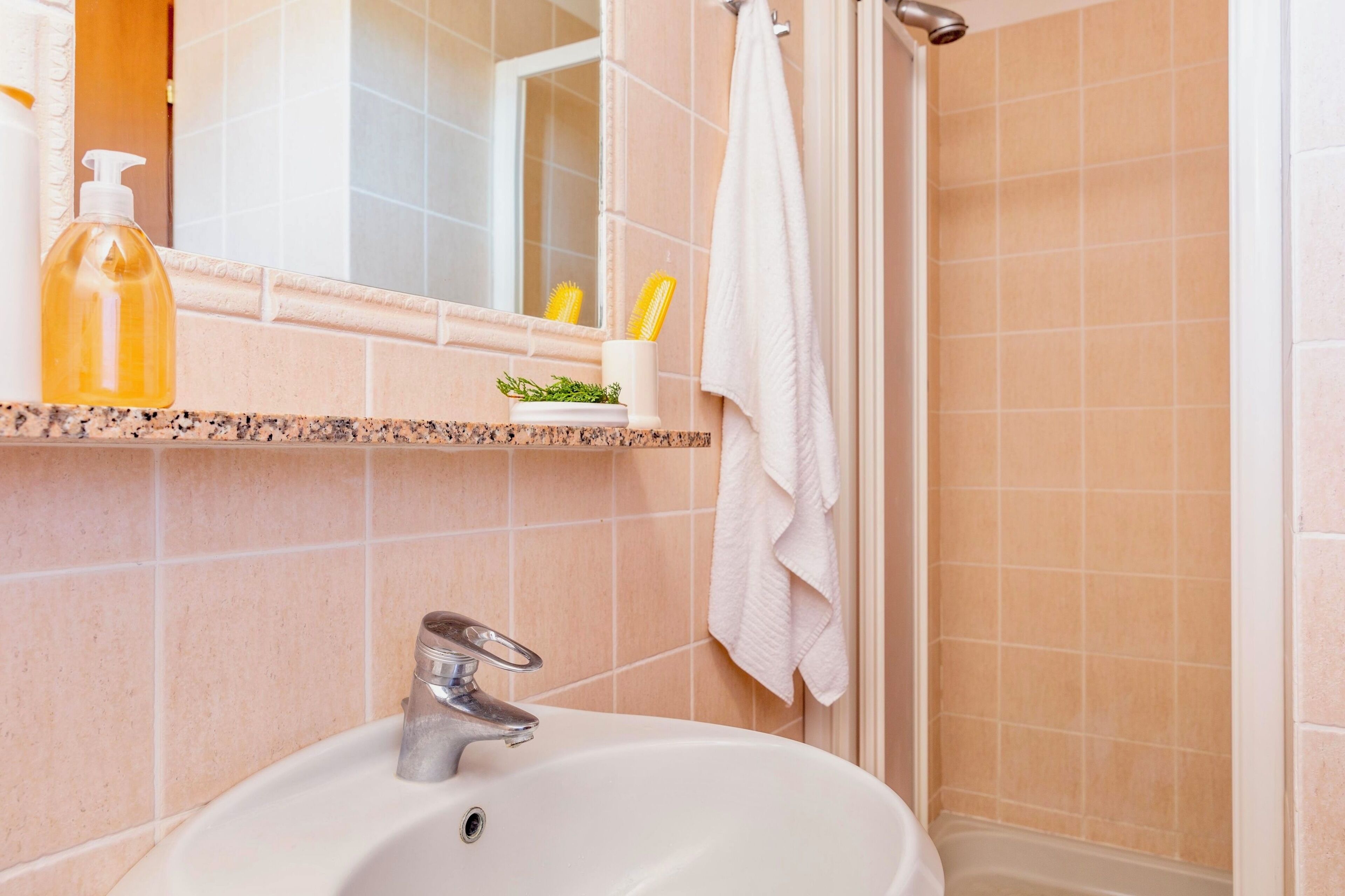 A bathroom with a sink, mirror, and toiletries.