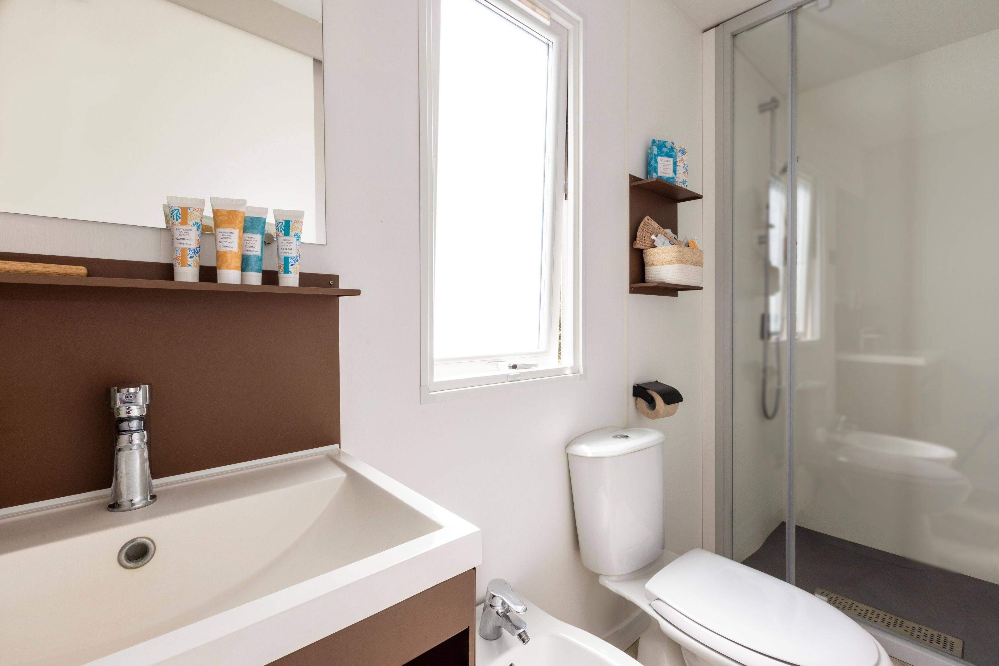 A modern bathroom with a white sink, a toilet, and a glass shower enclosure.