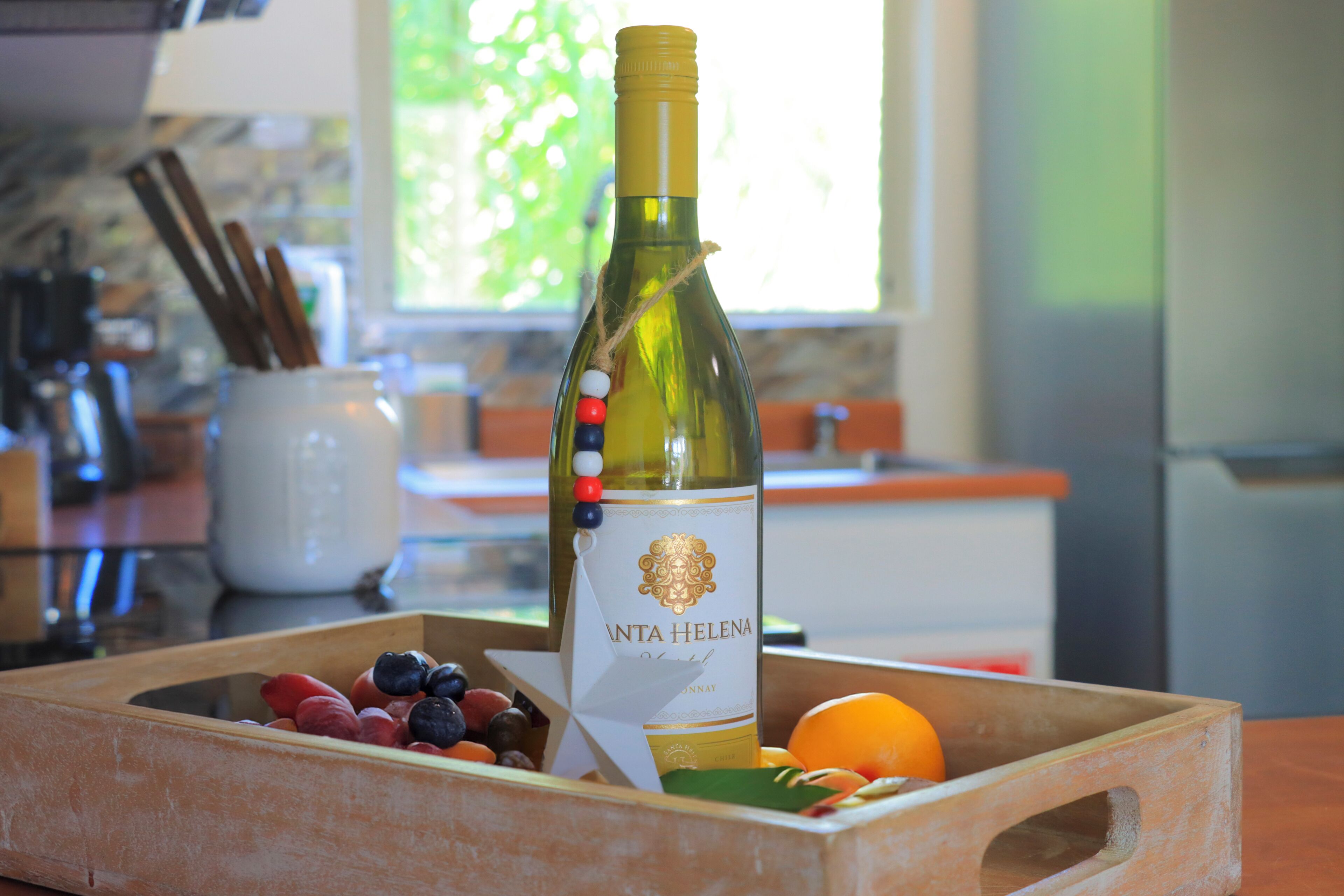 Een fles wijn met het etiket 'VINTA HELENA' in een houten kist met verschillende soorten fruit.
