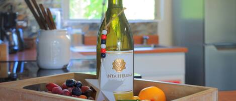 A bottle of wine with a label reading "VINTA HELENA" in a wooden crate containing various fruits.