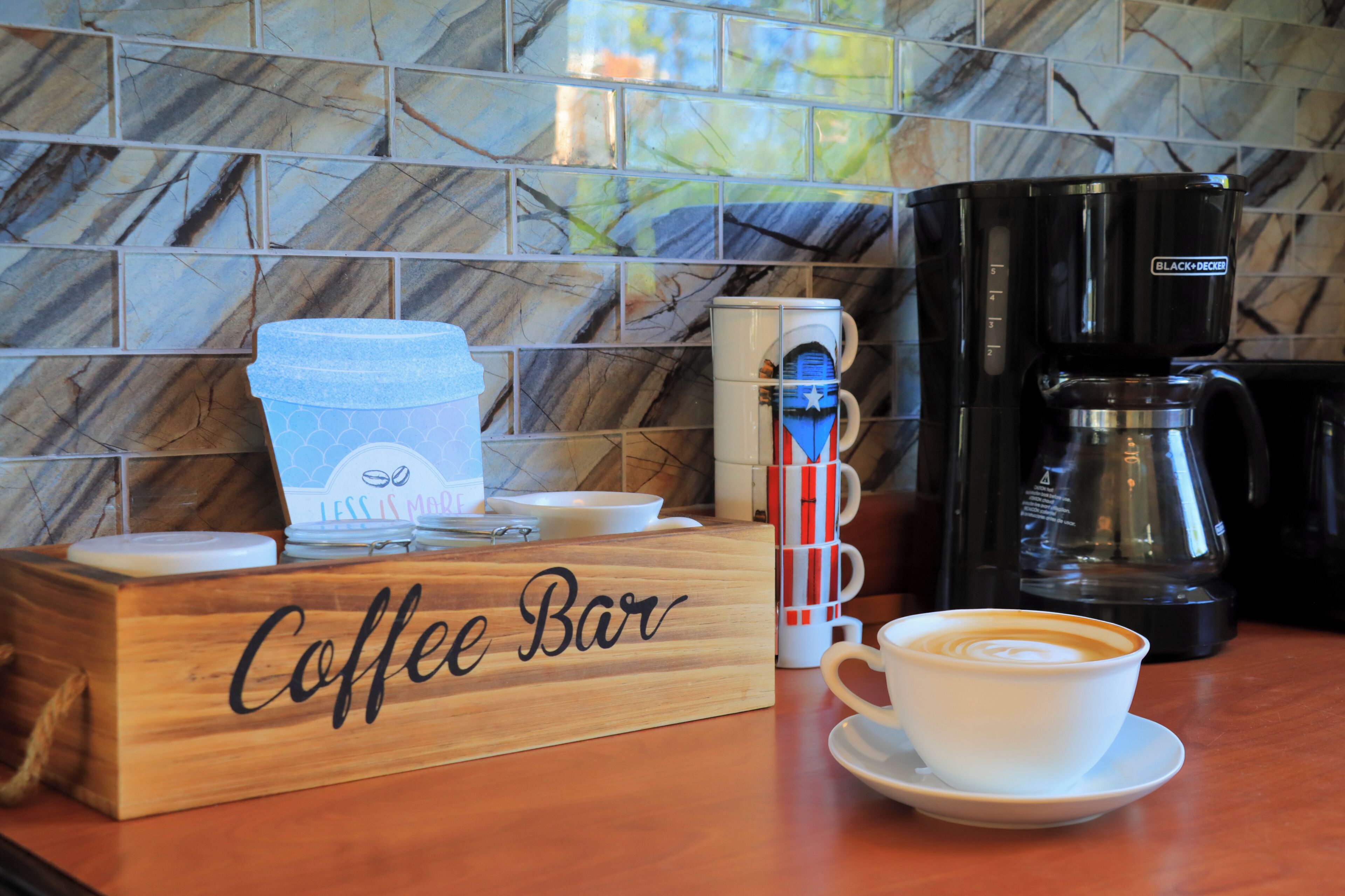 Un coin café aménagé avec une machine à café, des tasses et un panneau indiquant « Bar à café ».