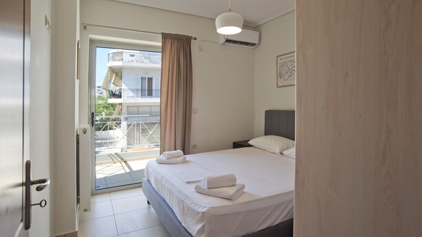 Un dormitorio con cama, mesita de noche, ventana con cortinas y un equipo de aire acondicionado.