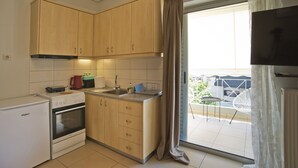 Una cocina compacta con armarios de madera, horno empotrado y un lavabo.
