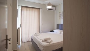 Habitación de hotel con cama, mesita de noche, aire acondicionado de pared y una puerta con una toalla.