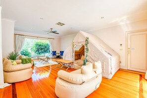 Ein Zeltraum mit Deckenventilator, einem Holztisch und einer Couch.