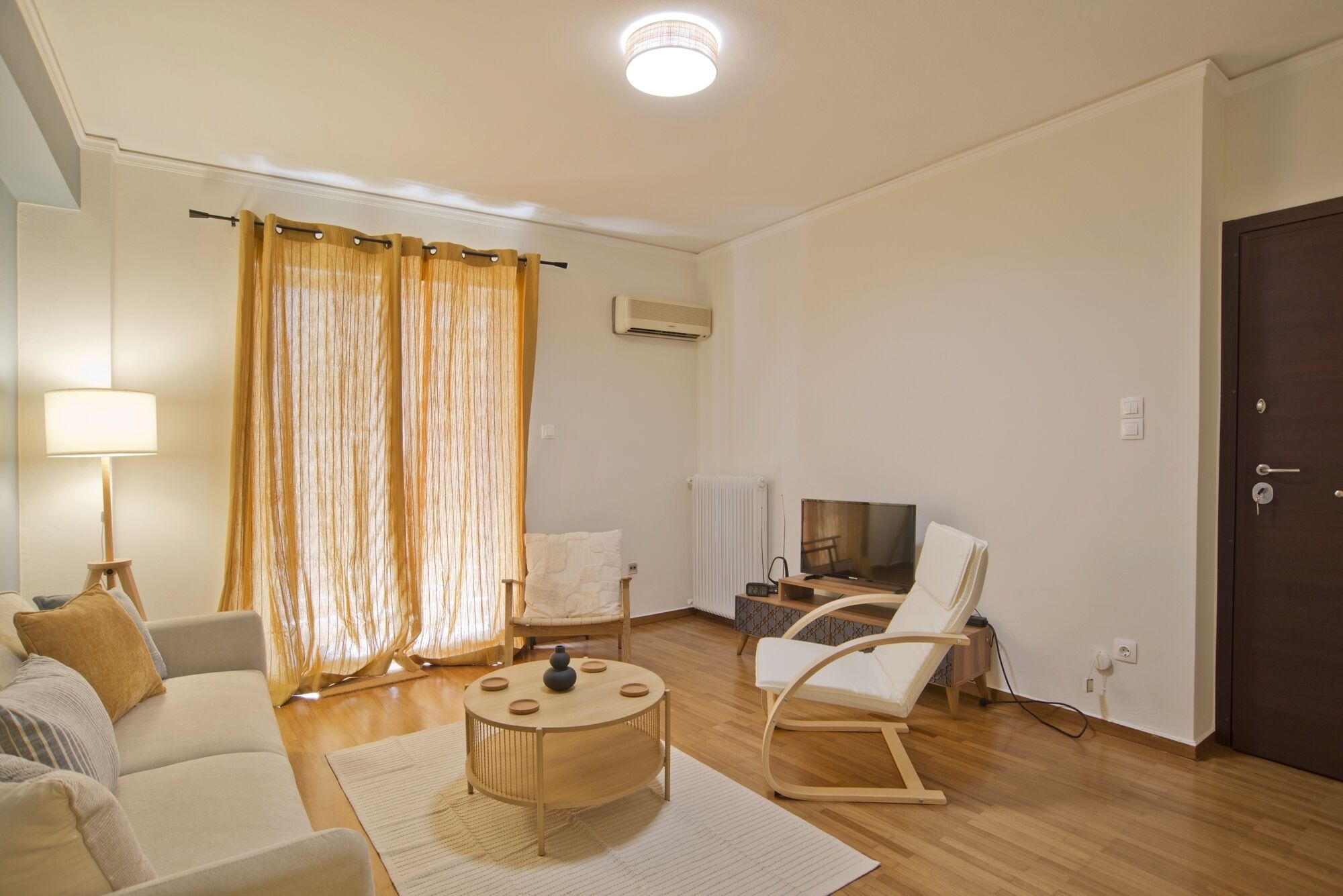 Ein Wohnzimmer mit Sofa, Couchtisch, Fernseher, Sessel und Lampe.
