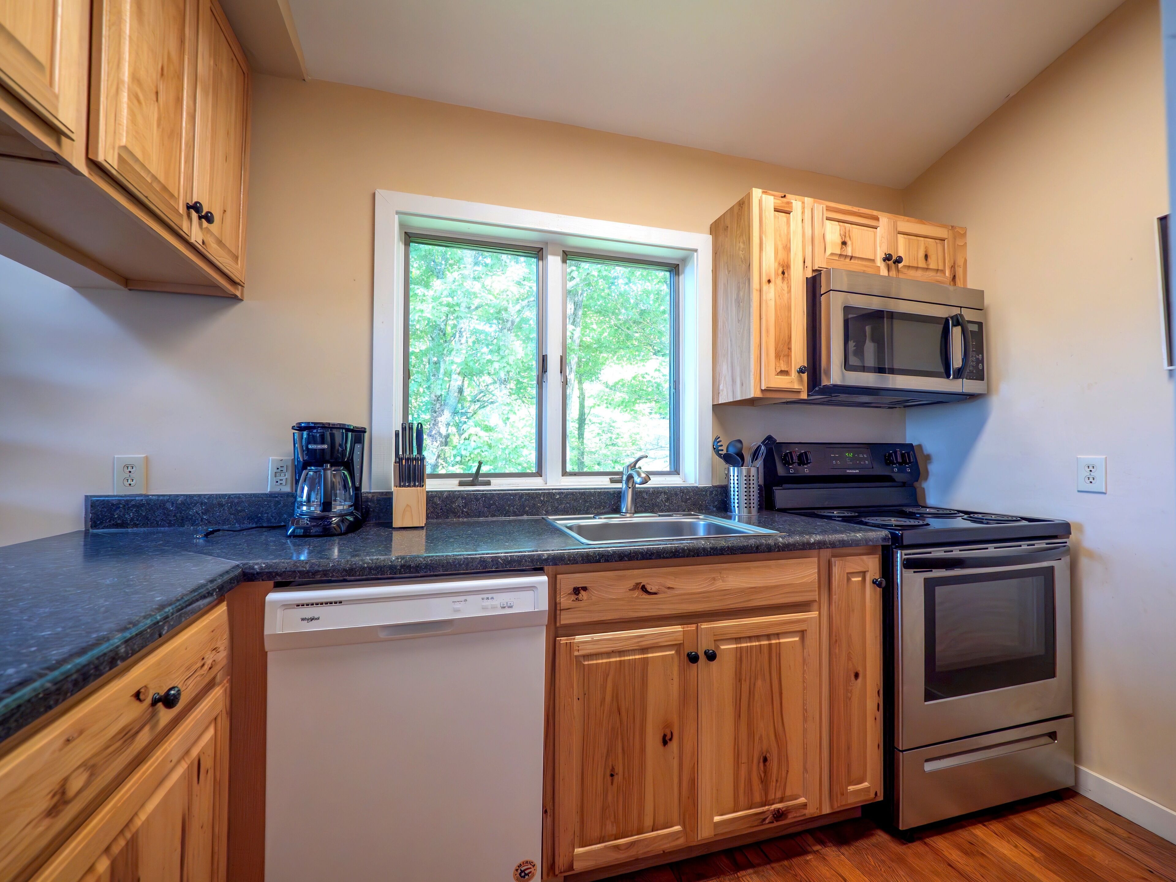 A kitchen with wooden cabinets, a built-in microwave, a dishwasher, and an oven.