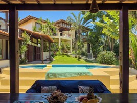 Vista de uma área de piscina com um espaço de estar coberto em primeiro plano.