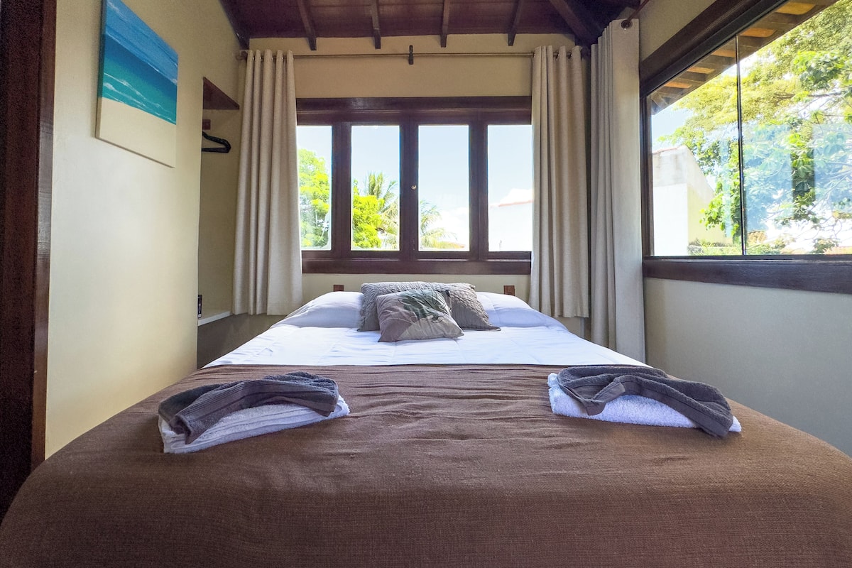 A neatly made bed with a brown cover, two pillows, and a folded towel on the bed.