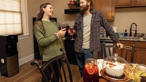 A kitchen with wooden cabinets, a stove, and a dining table with a cake and drinks.