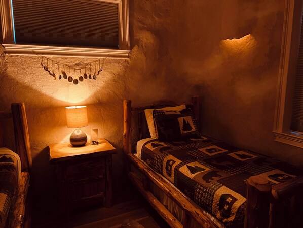 Una habitación acogedora con una cama individual, una mesita con lámpara y un adorno en la pared.
