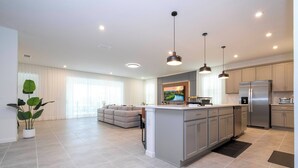 Uma cozinha moderna com ilha central, eletrodomésticos de aço inoxidável e iluminação pendente.