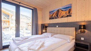 Habitació d'hotel amb un llit gran, un quadre d'una muntanya i vista d'un edifici a l'exterior.