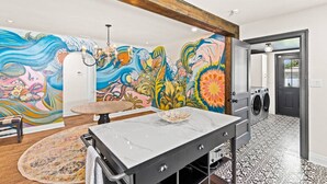 Un lavadero con un gran mural, una lavadora y una mesa de mármol.