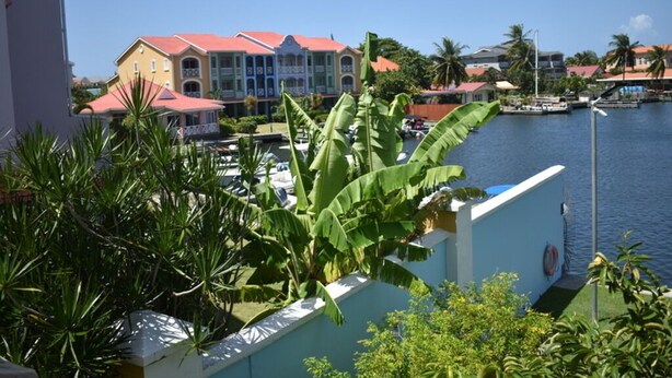 Vista costera con un edificio que tiene balcones y un puerto deportivo con barcos.