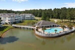 A resort with multiple buildings, a swimming pool, and a bridge over a body of water.