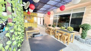 Un espace extérieur aménagé avec des tables et des chaises, un ventilateur et des lanternes en papier décoratives.