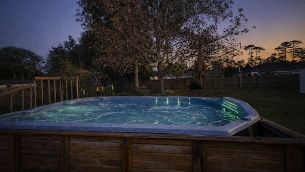 A hot tub in a backyard with a wooden deck and a tree. - Your Perfect Perdido Key Getaway (Pensacola)